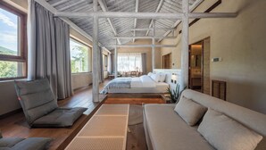 A spacious bedroom with a large bed, a sofa, and a chair. There are windows providing natural light and a view of the outdoors. - Hegu Villa Hotel (Changzhou)