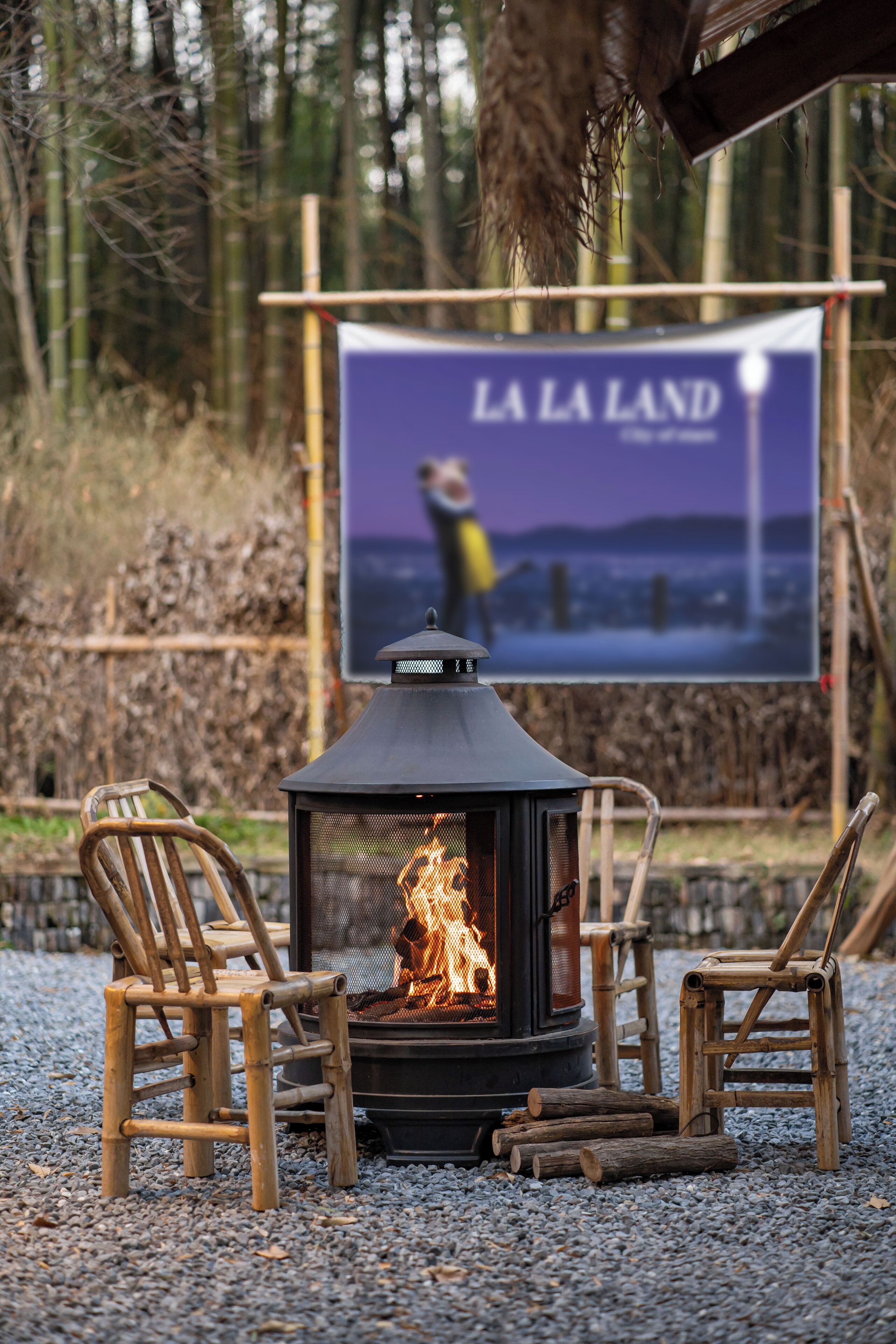 A wood-burning stove with two wooden chairs in front, a banner in the background, and a forested area.