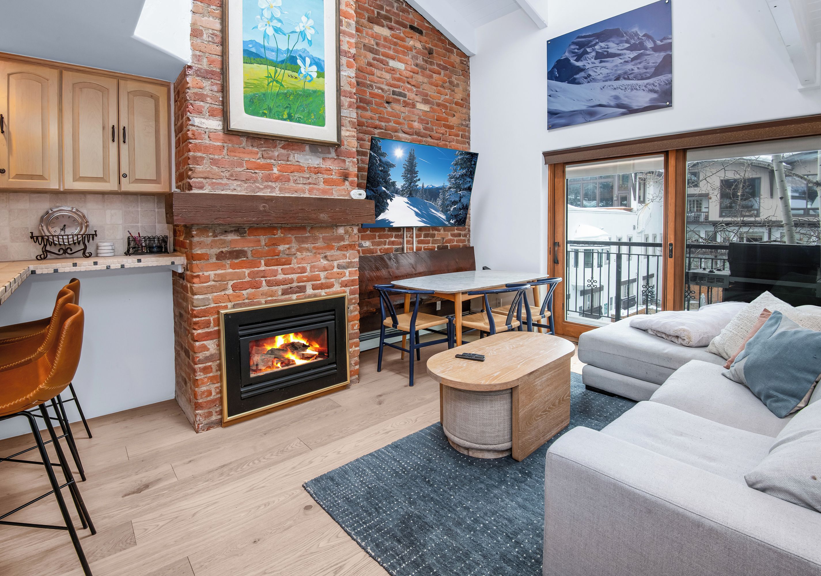 Una sala de estar acogedora con chimenea, un sofá, un comedor y un televisor montado en la pared.