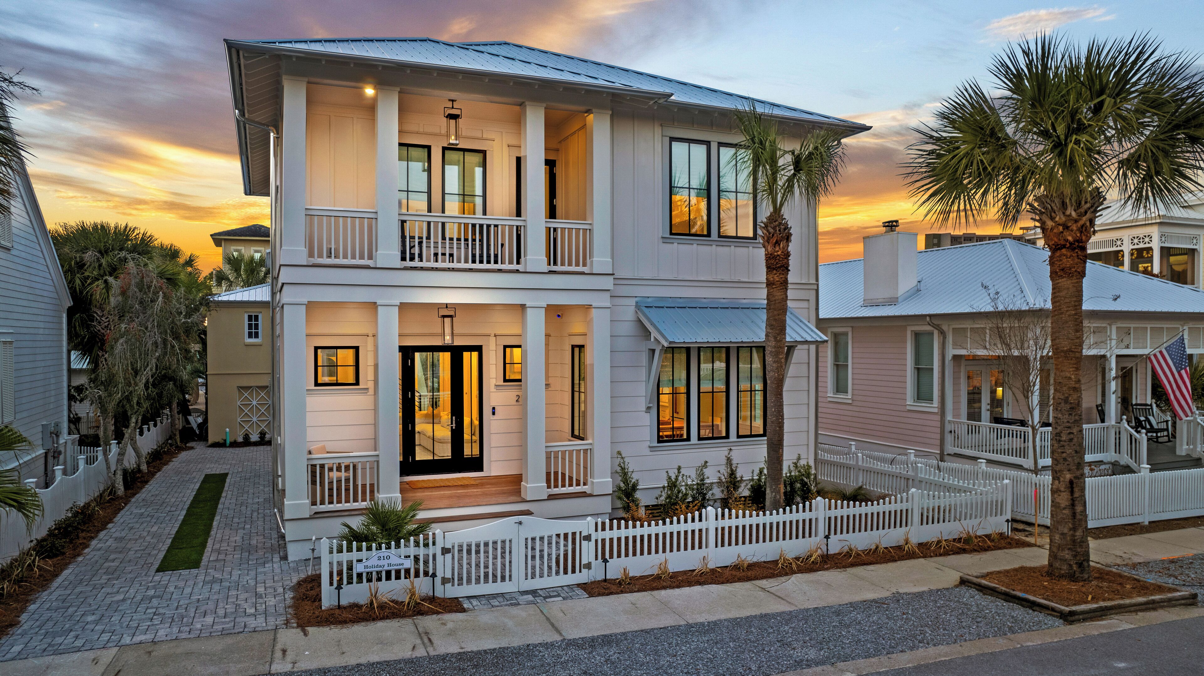 A two-story house with a balcony, a front porch, and a white picket fence.