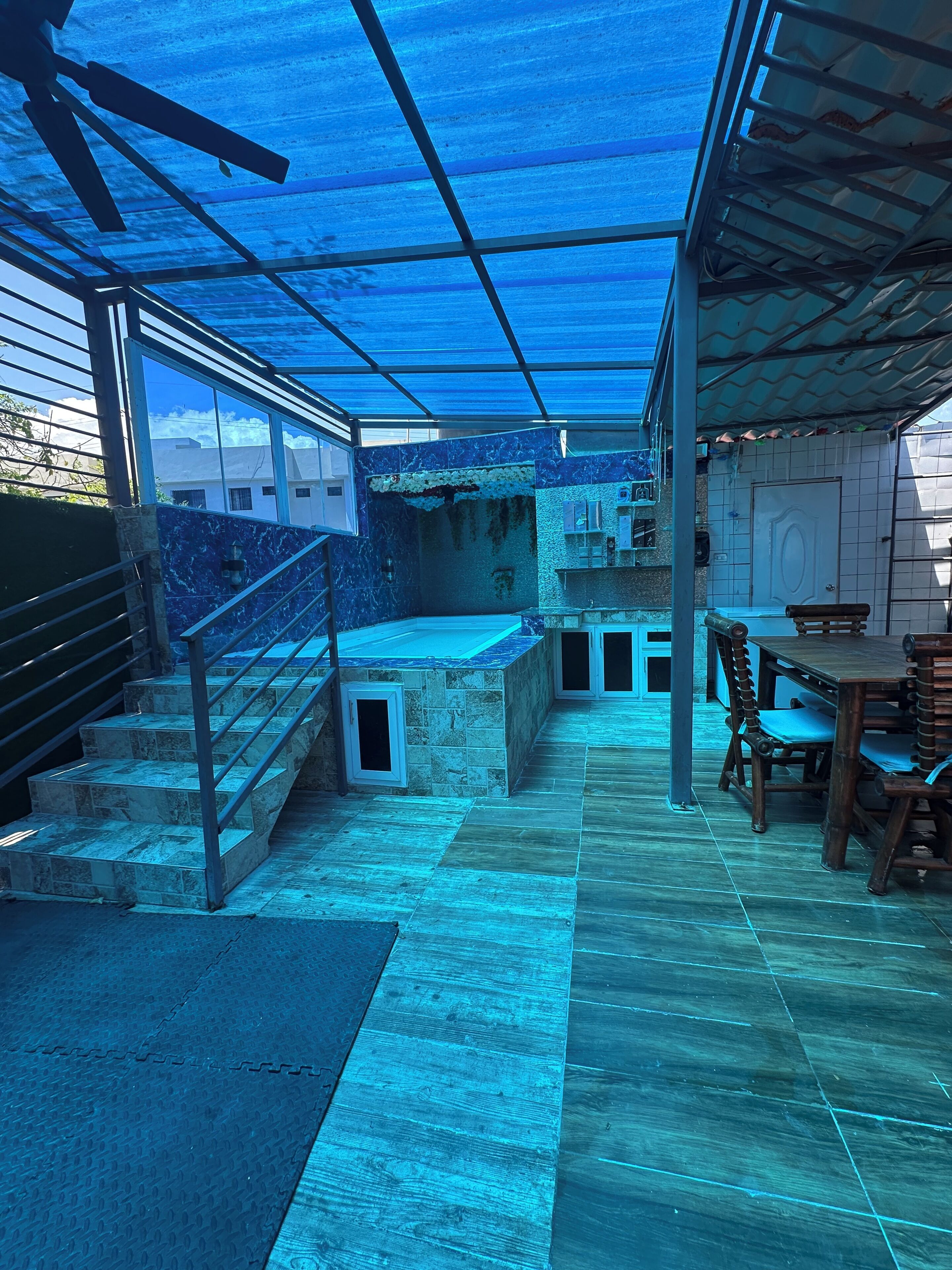 Un espace extérieur abrité, doté d’un sol en pierre, d’un escalier et d’une table à manger avec des chaises.