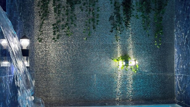 Un espace de bien-être doté d’un élément aquatique, d’un mur carrelé et d’un plafond décoré de fleurs.