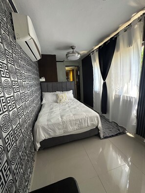 Un dormitorio moderno con una cama grande, papel tapiz estampado y un ventilador de techo.