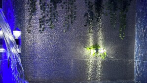 Un bain à remous doté de jets d’eau, entouré d’un mur texturé agrémenté de plantes suspendues.