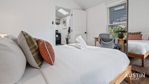 Un dormitorio moderno con una cama grande, un espejo, una mesita y vistas al exterior.