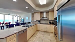 A modern kitchen with a large island, stainless steel appliances, and a view of the ocean. - 3BD/3BA Gulf-Front Condo at Caribe w. Pools, Tennis, Gym, Boat Slips + More (Orange Beach)