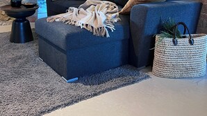 A cozy living room with a blue sofa, a woven basket, and a brick wall.