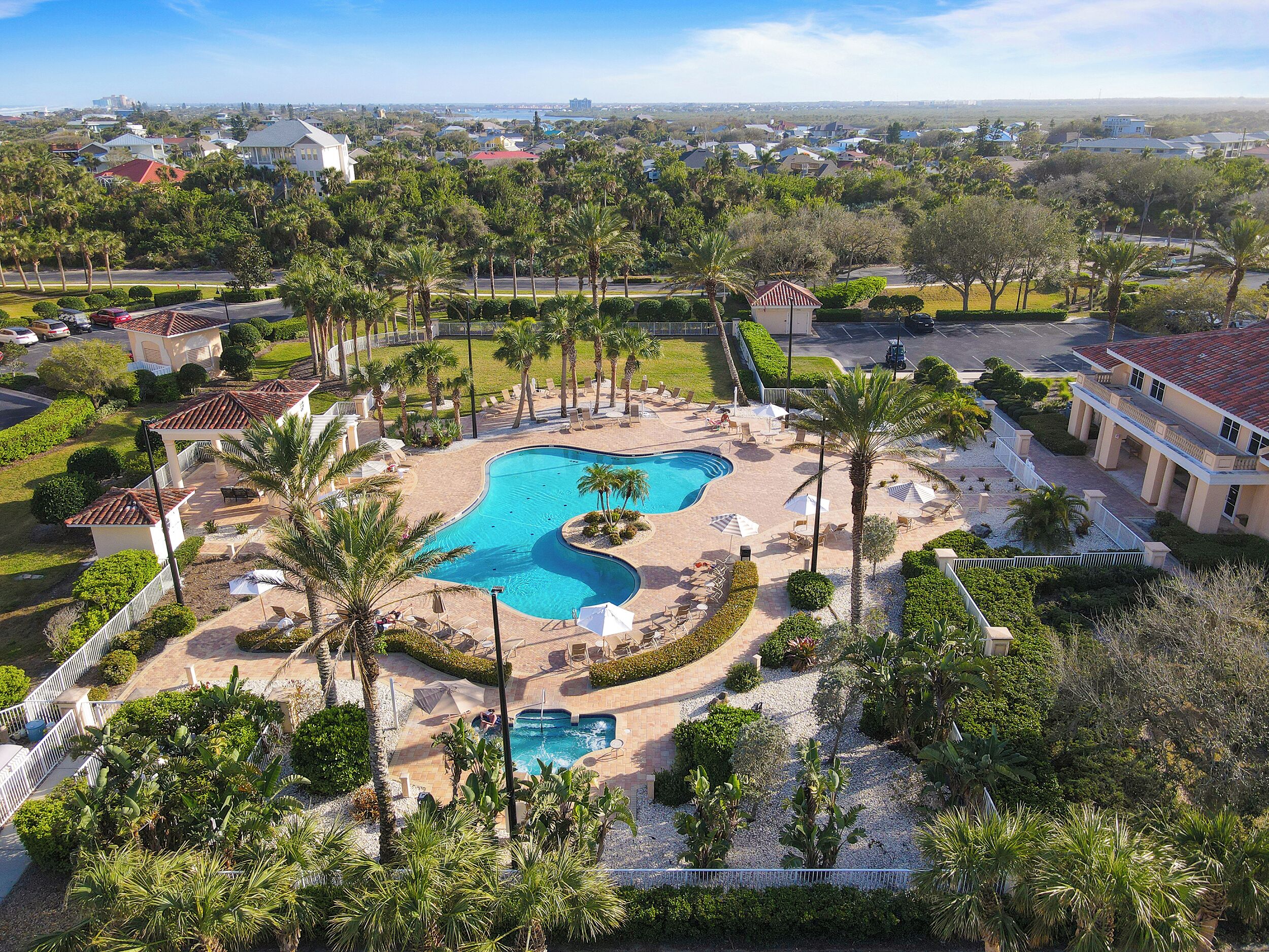 Een resort met een groot zwembad, palmbomen en uitzicht op de omgeving.