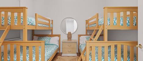 A room with two bunk beds, a bedside table with a lamp, a mirror, and a small rug.