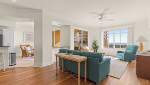 Amplia sala de estar con piso de madera, sofá color turquesa y ventilador de techo.