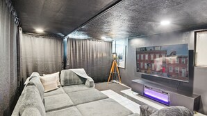 A modern room with a large gray sectional sofa, a small table, and a flat-screen TV mounted on the wall. - 5 minutes to Stadium/Casino/PNC. Spacious house with WiFi, Game/Movie Rooms (Pittsburgh)