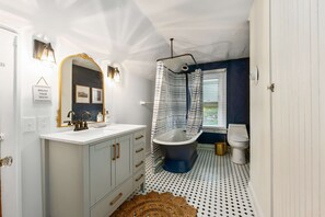 Une salle de bain avec un meuble-lavabo blanc, une baignoire sur pieds et des toilettes.