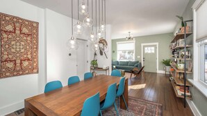 Un comedor con una mesa de madera, sillas azules, lámparas colgantes y un tapete grande con diseño.