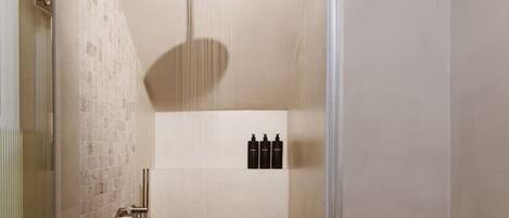 Une douche moderne dotée d’un pommeau de douche à main, d’une porte en verre et d’un sol carrelé.