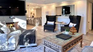 Un salon moderne avec une cheminée, des sièges confortables, une table basse et un téléviseur fixé au mur.