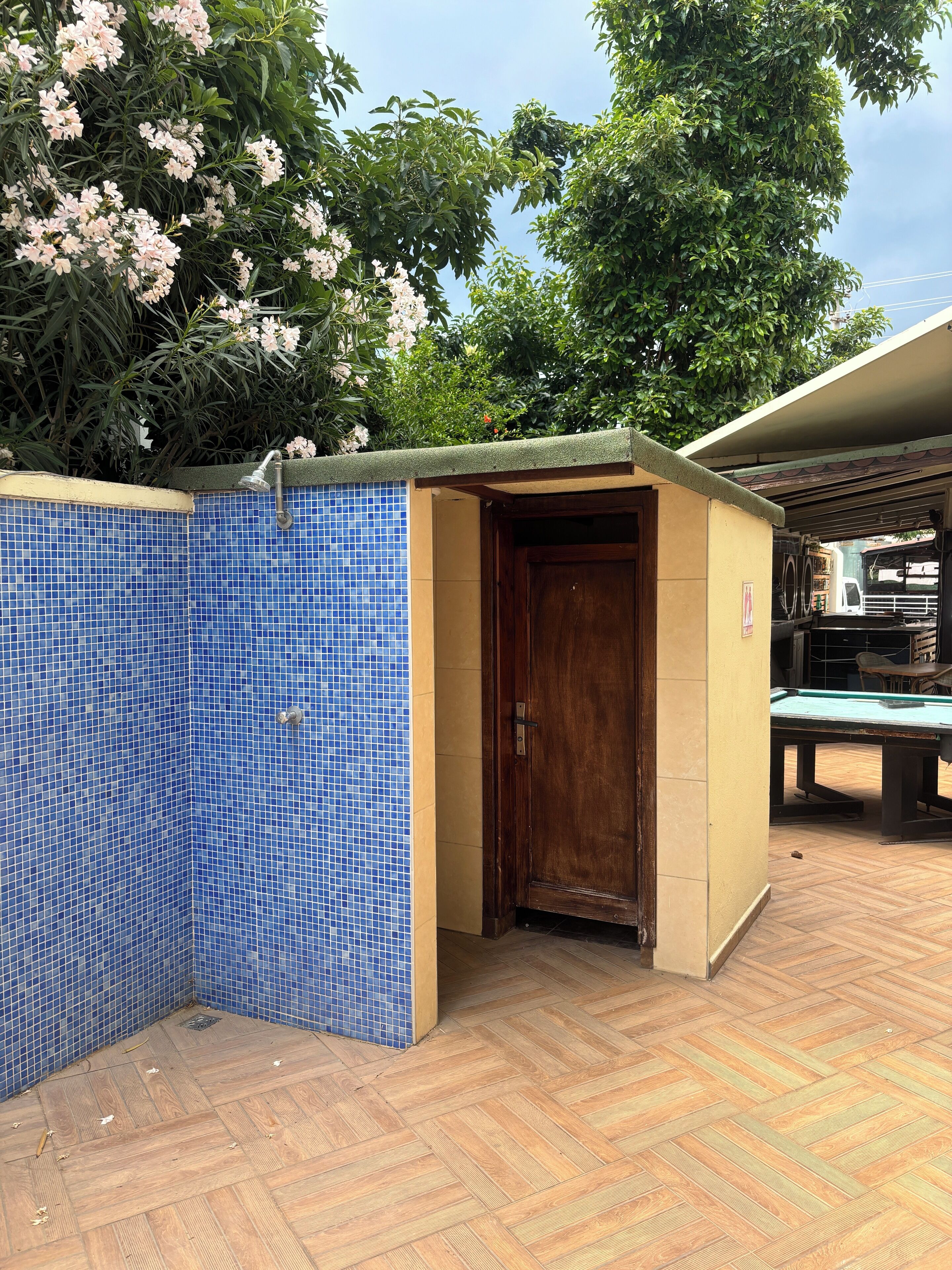 A small, enclosed pool area with a wooden door and a blue tiled wall.