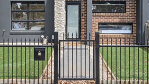 Un bâtiment moderne doté d’une cheminée en pierre, d’une façade en briques et d’un portail en métal noir.