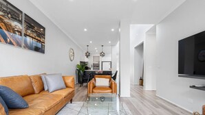 Un salon moderne avec un canapé en cuir, une table basse en verre et un coin repas à l’arrière-plan.