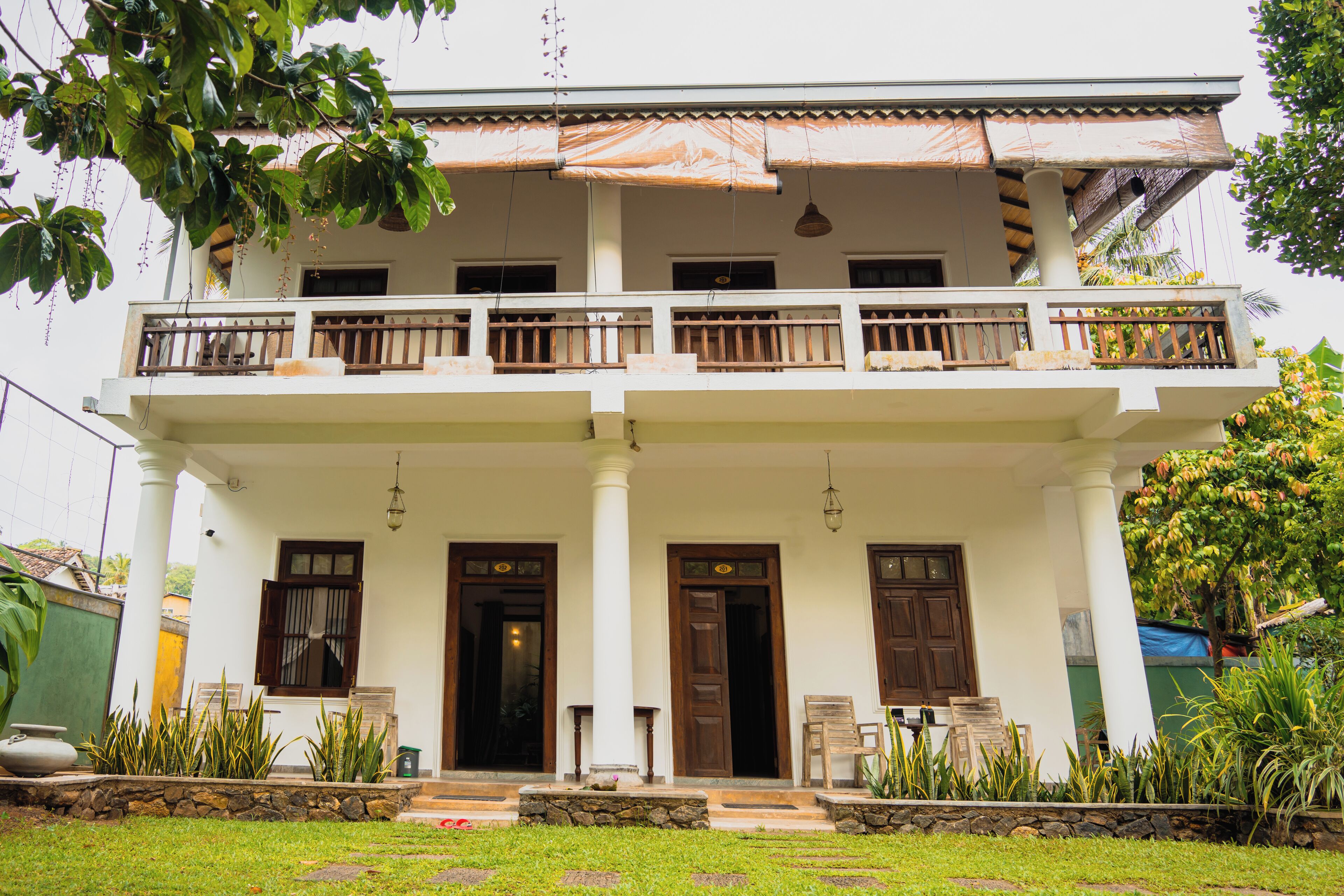 A two-story building with a balcony, large windows, and a stone foundation.