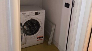 A compact laundry room with a white washing machine, a radiator, and a tiled floor. - Studio apartment "Zone" (Lombardia)