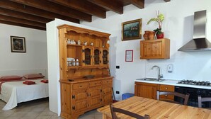 A kitchen with wooden cabinets, a stove, and a dining table with chairs. - Studio apartment "Zone" (Lombardia)