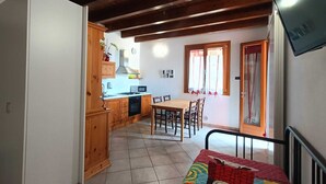 A compact kitchen with wooden cabinets, a dining table, and chairs. - Studio apartment "Zone" (Lombardia)