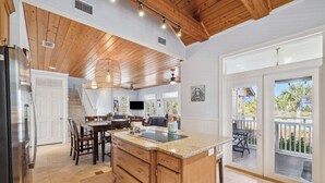 A spacious kitchen with a large island, wooden ceiling, and a sliding glass door leading to an outdoor area. - Foosball | Hot Tub | LSV | Pool Access (Port St Joe)
