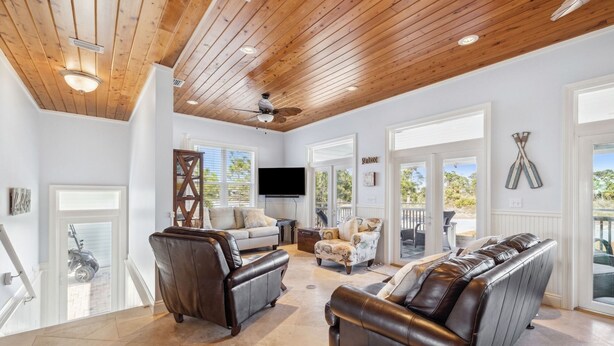 A spacious living area with leather sofas, a flat-screen TV, and a ceiling fan. - Foosball | Hot Tub | LSV | Pool Access (Port St Joe)