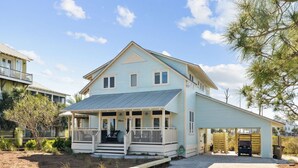 A two-story house with a porch, a covered garage, and a paved driveway. - Foosball | Hot Tub | LSV | Pool Access (Port St Joe)