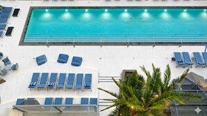 A large indoor swimming pool with blue lounge chairs and sun loungers arranged around it. - Alex 2BD Haven in Hollywood!Free parking and pool! (West Hollywood)