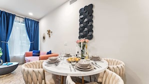 A dining area with a round table set for four, surrounded by upholstered chairs. - Alex 2BD Haven in Hollywood!Free parking and pool! (West Hollywood)