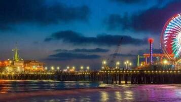 A pier with a large Ferris wheel and a building with lights.