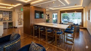 Une cuisine moderne dotée d’un îlot central, de tabourets de bar et d’un coin salon avec un canapé et des fauteuils.