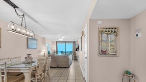 A spacious room with a dining area, a sofa, and a view of the ocean. - 🌞Emerald Surf 106: 1st Floor Gulf-Front Condo w/ Pool🌞 (Navarre Beach)