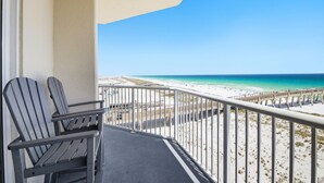 A balcony with two Adirondack chairs overlooking a beach with a pier. - ☀️🌴 Inn at Summerwind 501 - This Is It: Wrap-Around Balcony, Near Pier 🌴☀️ (Navarre Beach)