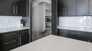 A modern kitchen with dark wood cabinets, white countertops, and a built-in oven. - Desert Dreams Retreat – Your Perfect Desert Getaway (3 Bedroom home & A Studio) (Moab)