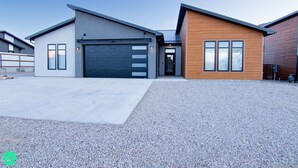 A modern two-story house with a garage, a driveway, and a gravel front yard. - Desert Dreams Retreat – Your Perfect Desert Getaway (3 Bedroom home & A Studio) (Moab)