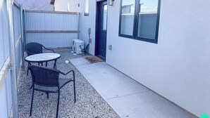 Un piccolo patio esterno con tavolo e sedie, una porta e una finestra.