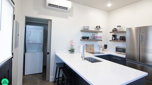 Una cucina moderna con lavatrice e asciugatrice integrate, elettrodomestici in acciaio inossidabile e un piano di lavoro bianco.