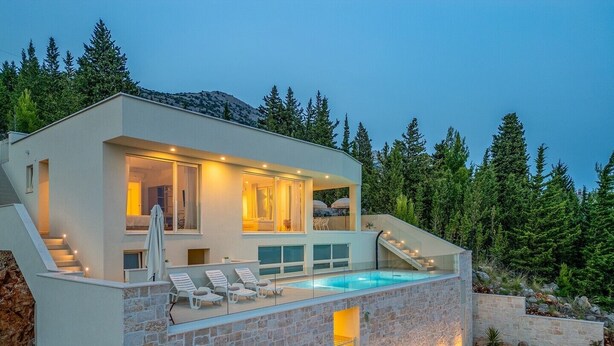 Una casa moderna con piscina, una escalera y vistas a árboles.