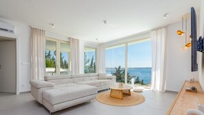 Una sala de estar moderna con un sofá grande, una mesa de centro y vista al mar.
