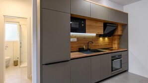 A modern kitchen with grey cabinets, a wooden countertop, a sink, a microwave, and an oven.