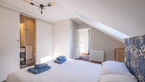 Un dormitorio moderno con una cama grande, tragaluz, vestidor y pared con diseño.