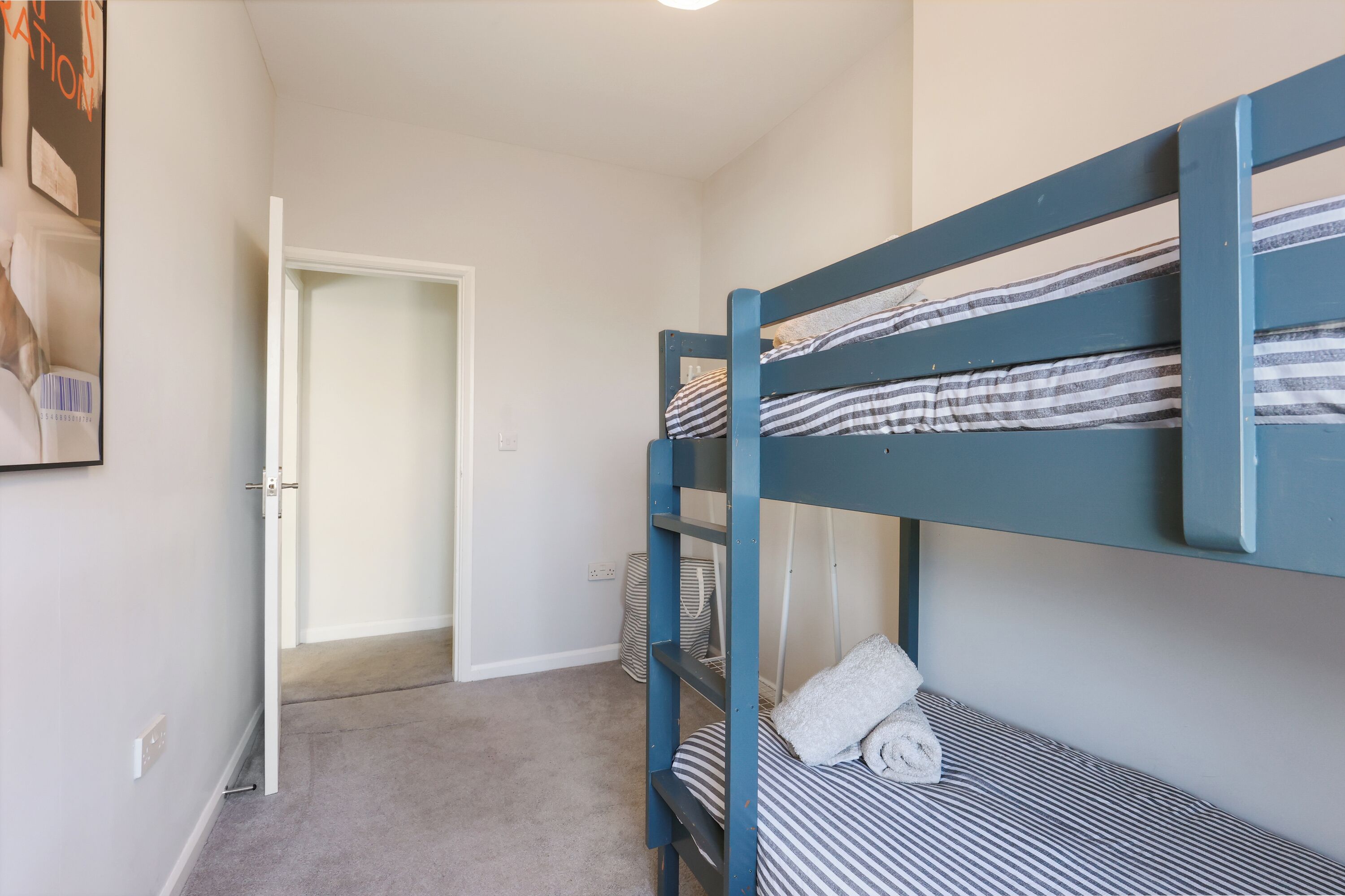 A bunk bed with striped bedding, a white door, and a carpeted floor.