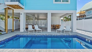A modern house with a pool, outdoor seating, and a covered patio area.