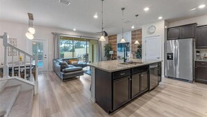A modern kitchen with a central island, stainless steel appliances, and pendant lighting. - The Solterra Resort Retreat (Davenport)