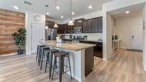 A modern kitchen with dark cabinets, stainless steel appliances, and a central island with bar stools. - The Solterra Resort Retreat (Davenport)
