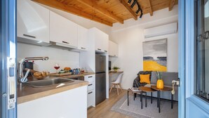 Una cucina moderna con mobili bianchi, un frigorifero in acciaio inossidabile e un soffitto in legno.