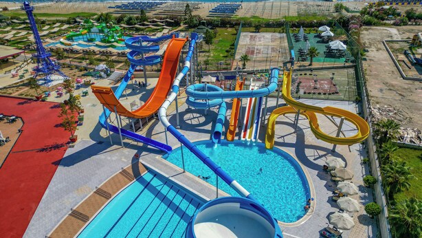 A water park with multiple slides and pools, surrounded by beach areas and umbrellas. - Grand Cortez Halal Family Hotel - All Inclusive  (Alanya)