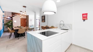 Una cocina moderna con una isla central, muebles blancos y salpicadero de mármol.